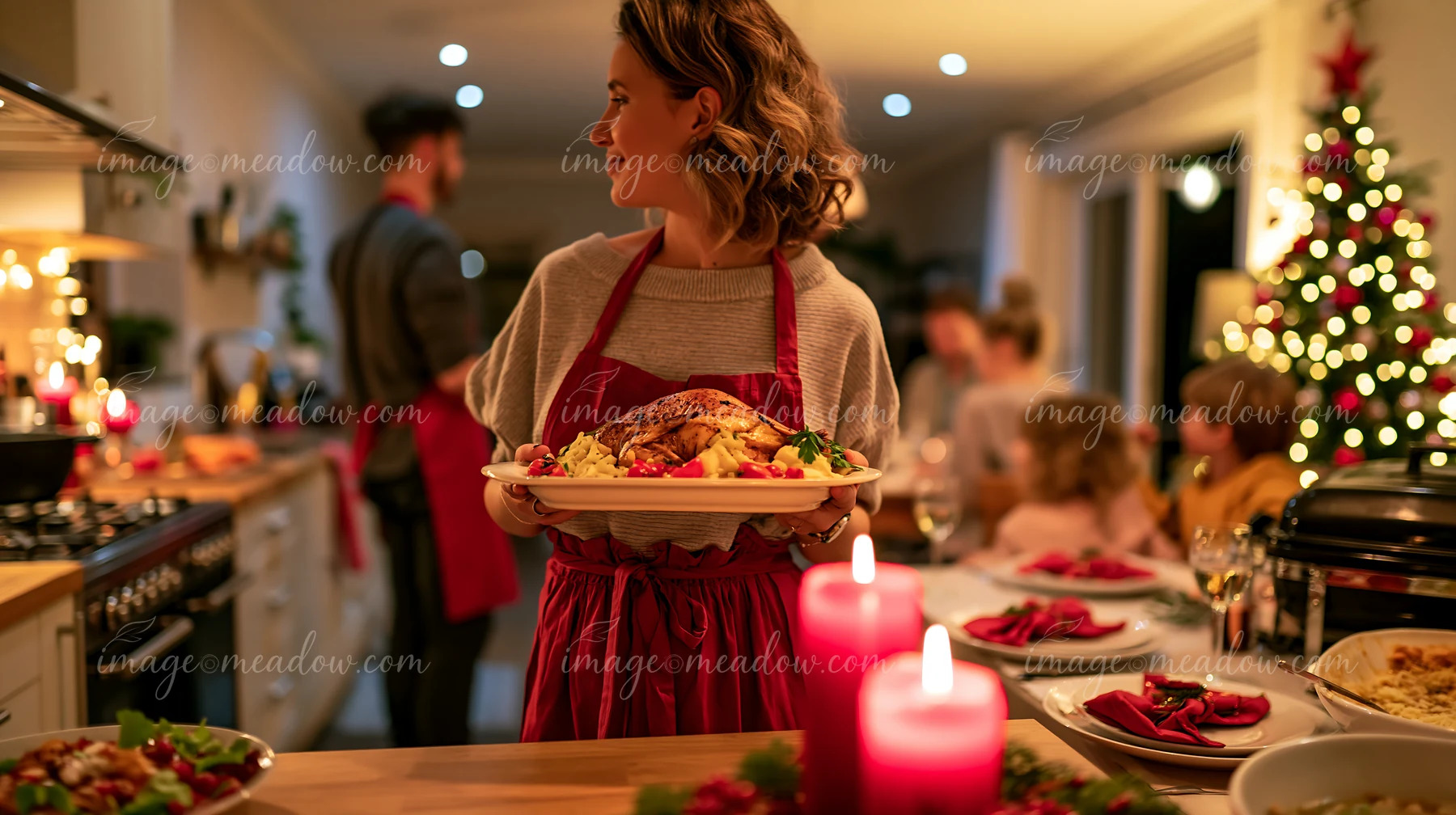Woman carries a platter of roast turkey toward family gathered at a Christmas dining table.