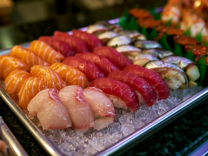 A variety of sushi types are arranged neatly on a tray filled with ice, showcasing vibrant colors and fresh seafood.