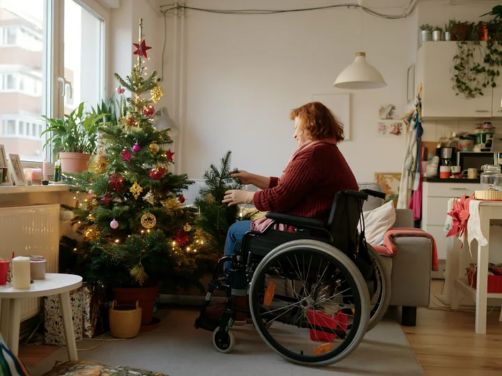 A woman in a wheelchair decorates a small apartment for the holidays.