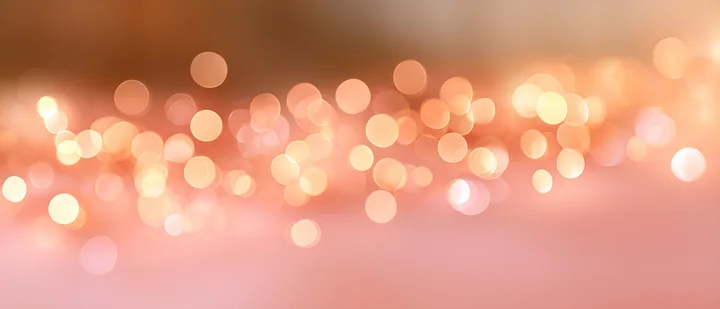 Bokeh lights in warm tones are scattered across a soft surface, giving a festive feel.