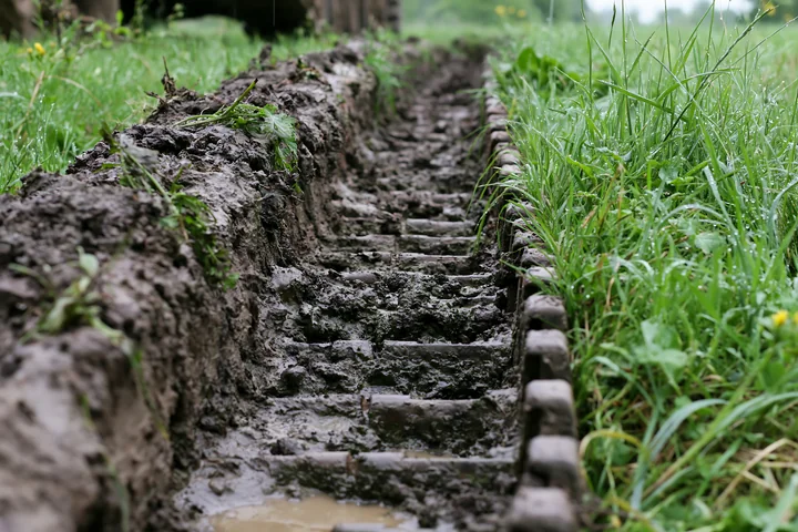 Panzer tank tracks are visible in a muddy area with grass surrounding them.