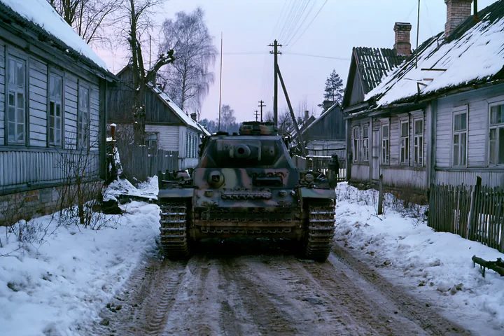 A panzer tank moves through a quiet village covered in winter snow.