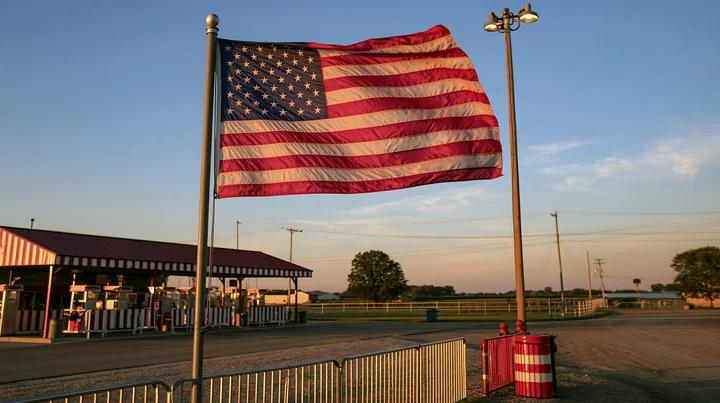 An American flag flying in strong wind at an outdoor event venue during evening light.