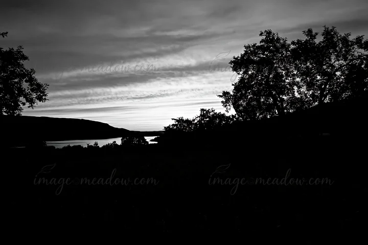 The scene shows an apple meadow in the highlands during sunset. The sky has pink and purple hues, reflecting off a river in the distance surrounded by trees. Pr