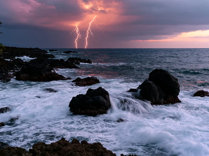 Lightning strikes illuminate the dark clouds above the coastline as waves crash against the rocky shore.