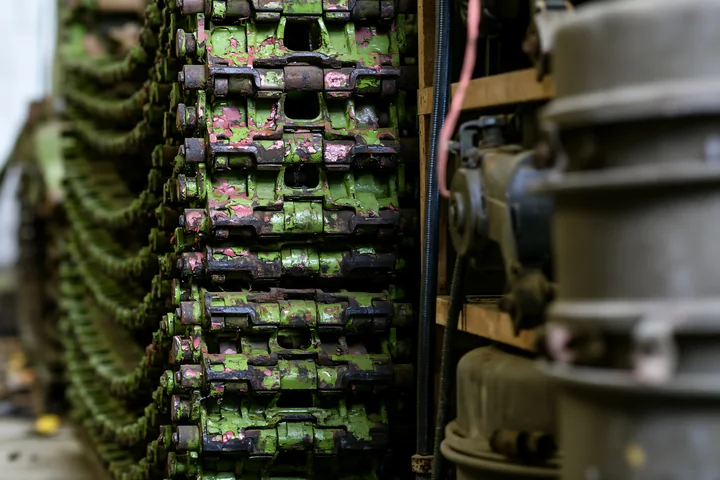 Panzer tank tracks close-up show a detailed view of the metal components stacked in a storage area, with signs of wear and camouflage paint visible on the surfa