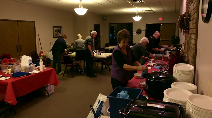 Volunteers are setting up a buffet for a charity event in a community hall.