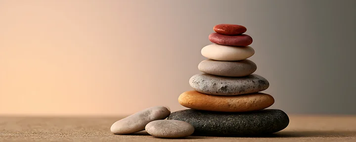 A balanced arrangement of smooth stones includes various colors and sizes, resting on a flat surface with a blurred background.