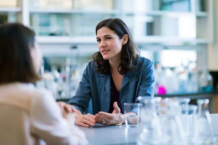 A businesswoman talks with an employee in a lab setting.