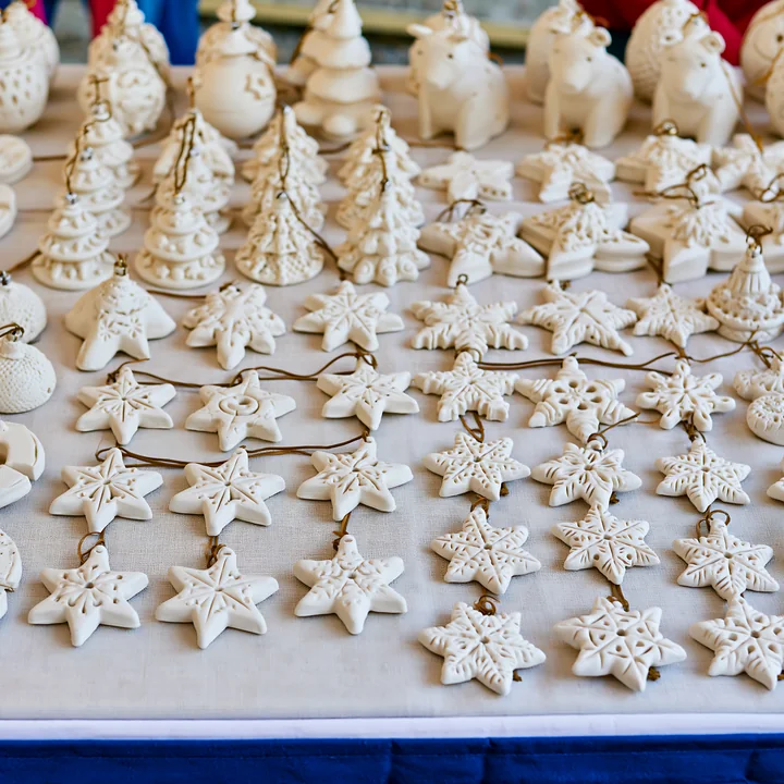 A Christmas market stall showcases various handmade ornaments arranged neatly.