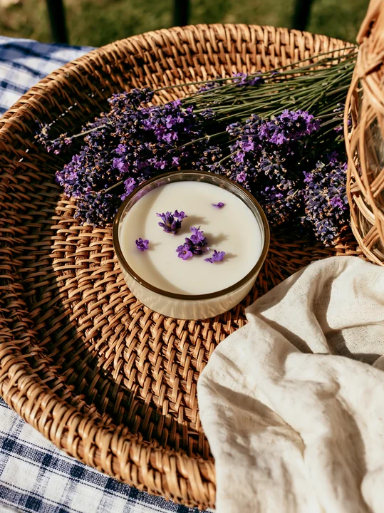A clear bowl holds a cream dose with lavender flowers on top, placed in a woven basket.