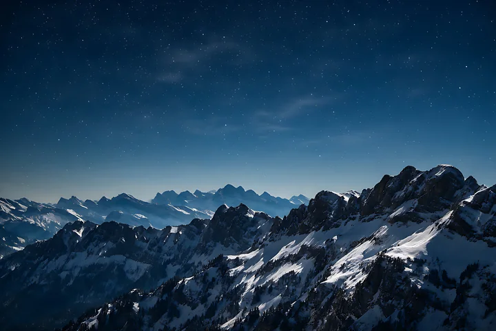 A clear night sky reveals a backdrop of towering Swiss mountains, covered with snow and illuminated by countless stars.