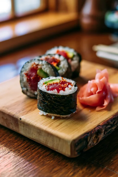 A close-up view of a spicy tuna roll served on a wooden platter.