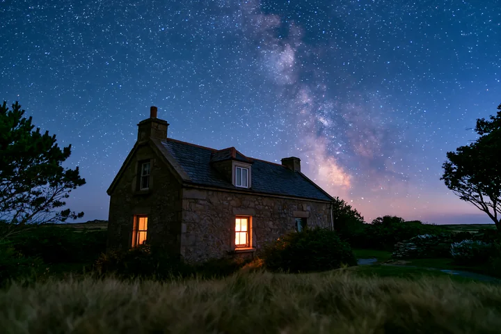 A country house is visible at night with the Milky Way shining above.