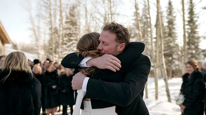 A couple shares an emotional embrace during their wedding ceremony in a snowy outdoor setting.
