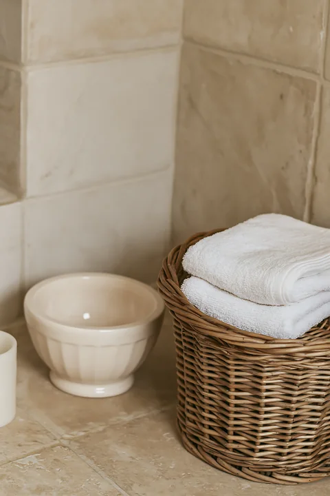 A cream dose is placed beside a folded white towel in a bathroom.