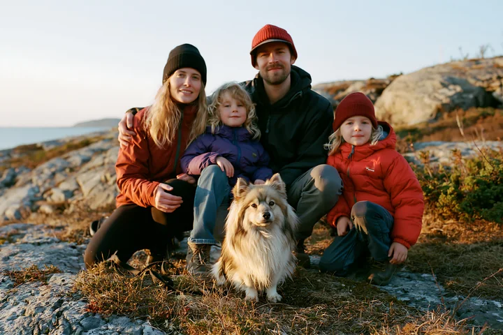 A family gathers on a rocky outdoor setting with their rare dog breed.