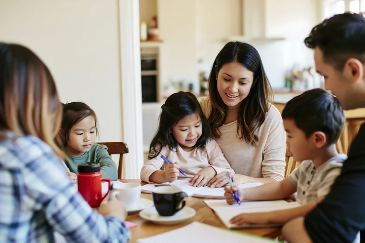 A family sits around a table in a cozy kitchen, engaging in a fun activity.