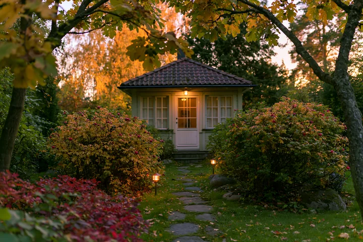 A garden house stands empty with lights along the pathway leading to its door.