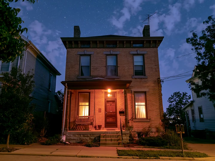 A house with a porch swing sits under a starry sky.