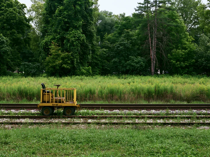 A maintenance cart sits on railway tracks next to a meadow alongside railway tracks.