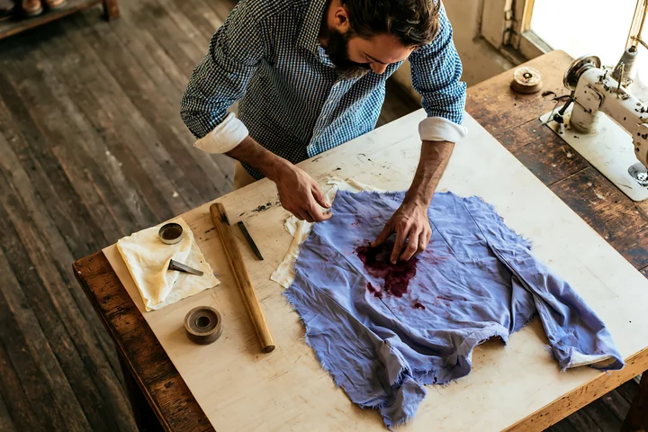 A man is working on cleaning a stained silk garment in a craft workshop.