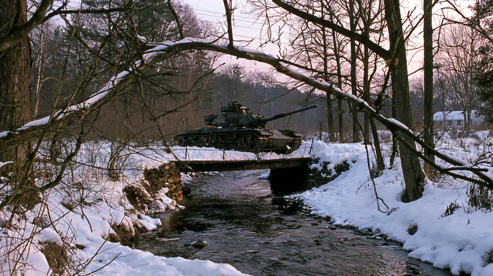 A panzer tank in winter snow moves quietly beside a creek surrounded by trees.