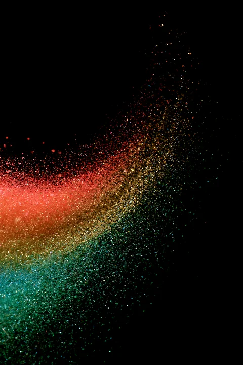 A swirl of colored salt and glitter creates an abstract pattern against a black background, showcasing vivid colors and fine textures.