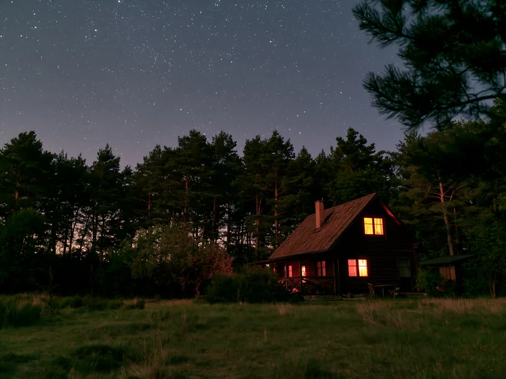 A villa stands peacefully beneath a star-filled sky, surrounded by trees.