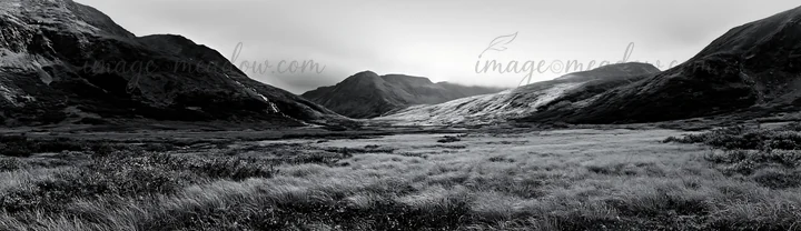 A view of an alpine meadow featuring a waterfall in the distance. The scene shows mountains and valleys, with grass covering the ground. Fog hovers above the la