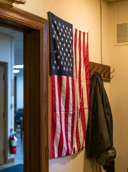 An American flag hanging vertically on a wall inside a building.