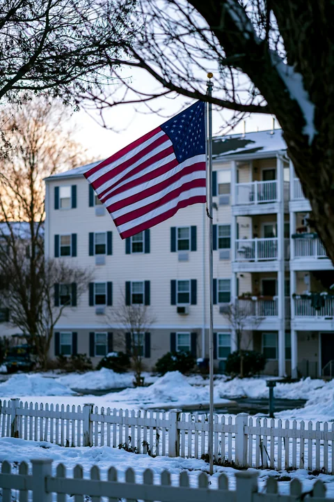 An American flag outside an apartment building waves in the cold winter air.