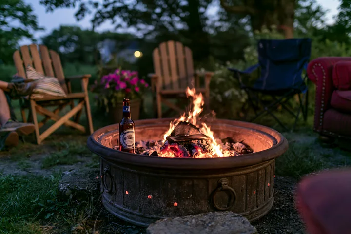 An empty bottle after party sits beside a fire pit surrounded by chairs.