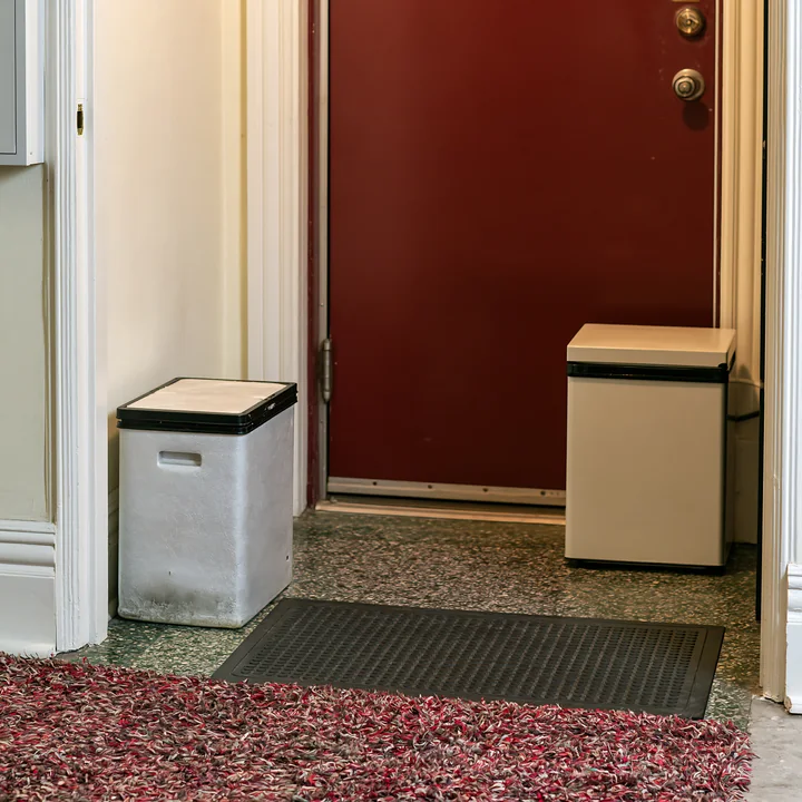 An insulated milk delivery box sits next to the front door on the apartment doorstep.