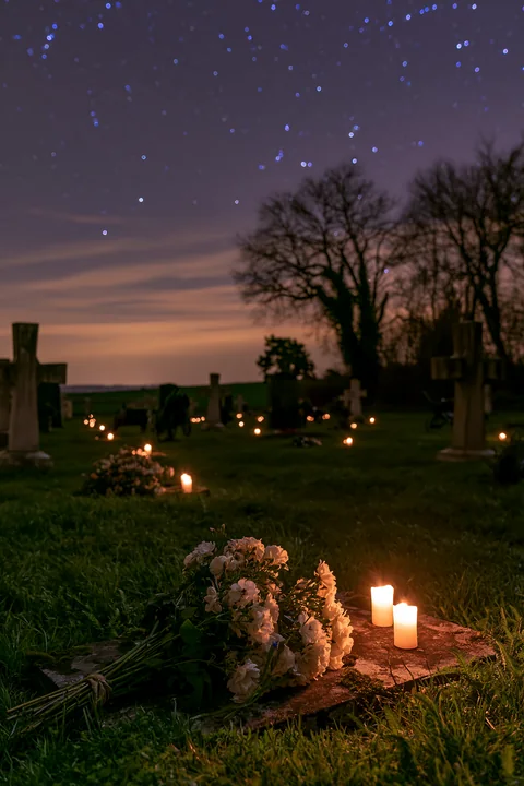 Candles light a soldiers' cemetery with flowers placed on graves.