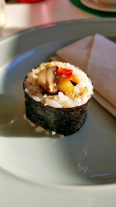 Close-up of a single sushi roll on a contemporary dining table with rice, nori, and colorful filling.