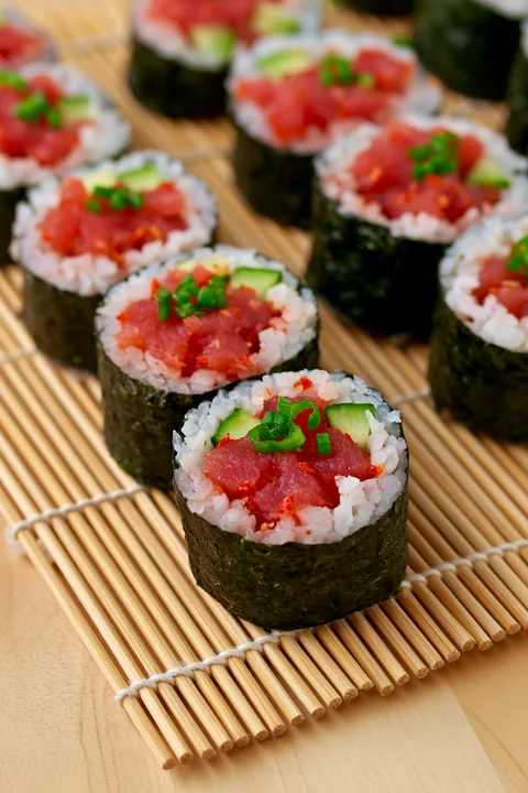 Close-up view of spicy tuna rolls arranged neatly on a bamboo mat.