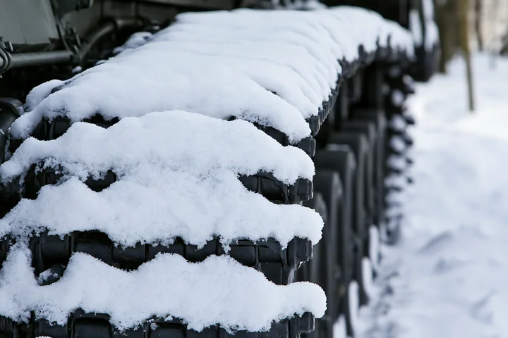 Panzer tank tracks close-up show snow accumulation on chain links in a winter setting.