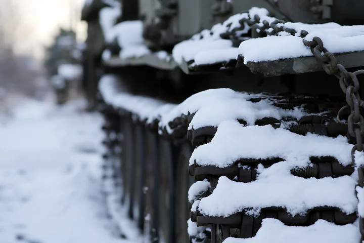 Snow covers the tracks of a panzer tank, highlighting the rugged texture and design.