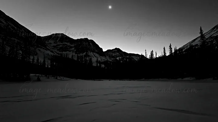 The scene shows a snowy Rocky Mountain Park meadow during twilight with mountains in the background and a crescent moon in the sky. Presented as a premium high-
