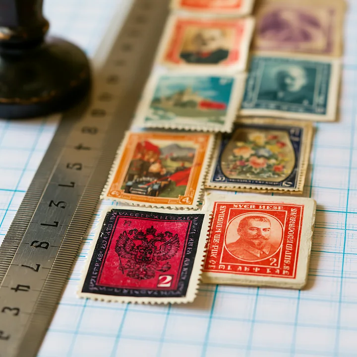 Soviet postage stamps are laid out on a grid surface next to a ruler for measurement.
