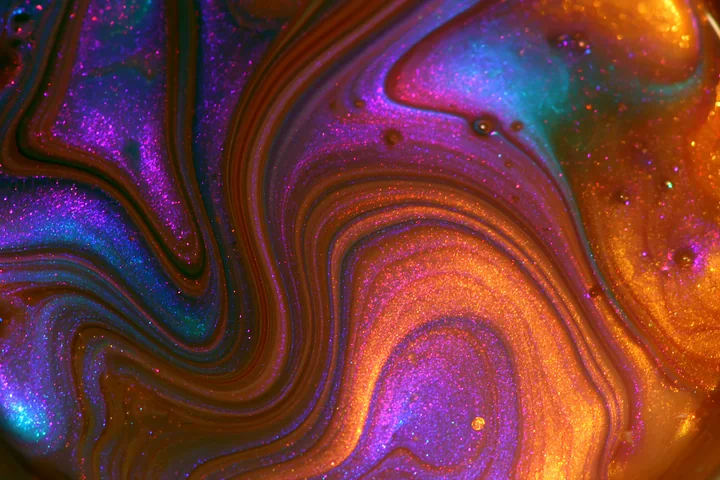 The colorful abstract swirl glittering pattern features vivid shades of purple, blue, and orange with shiny details that create an artistic effect.