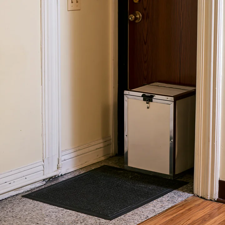 The insulated milk delivery box sits on the apartment doorstep near the entrance.