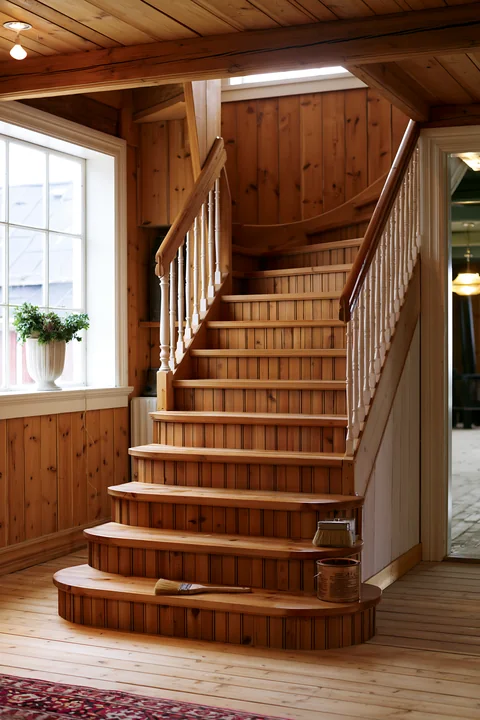 The wooden staircase leads upward in a country house during renovation.