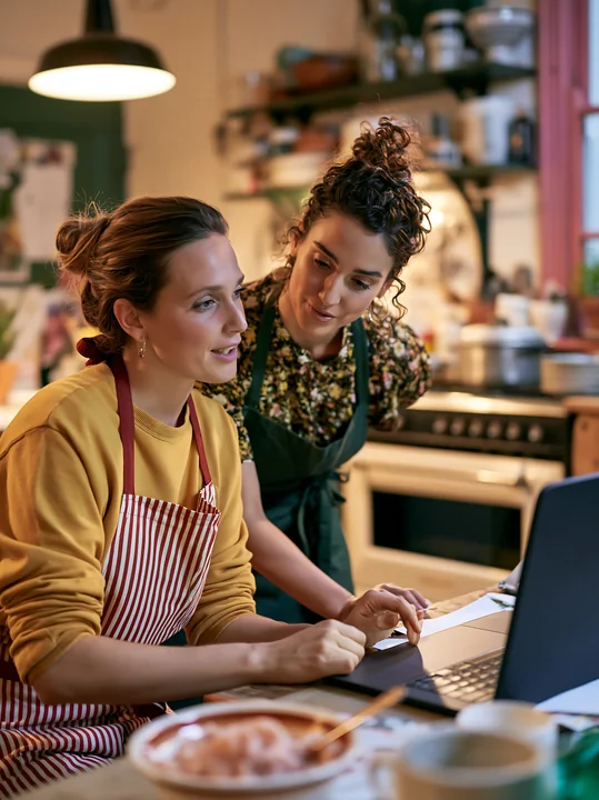 Two women are engaged in a conversation at a kitchen table.